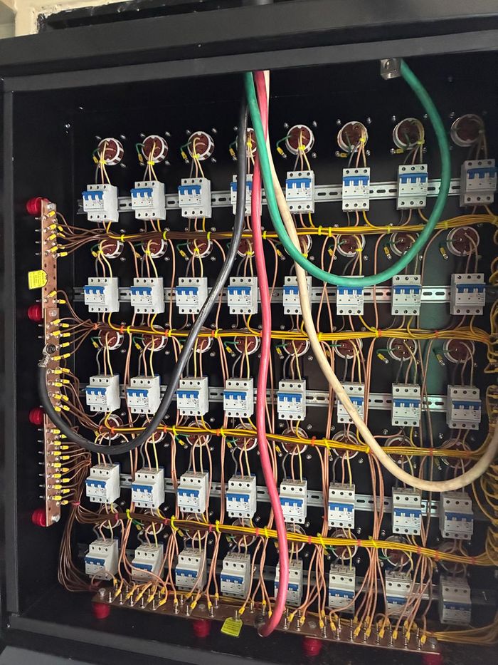 Behind the receptacle panel: rows of circuit breakers with neatly
                  labelled wiring.