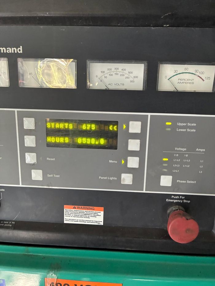 Cummins PowerCommand control panel with analogue meters, digital
                  display and red emergency stop button.