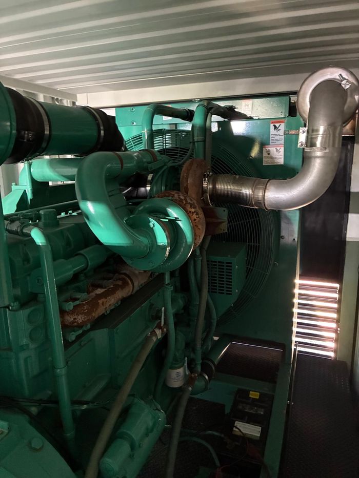 Green Cummins diesel engine inside the container, with turbo
                  piping and exhaust.