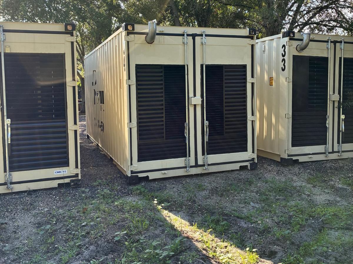 Several JD Power Packs generator containers standing in the yard,
                  louvred ends facing the camera.